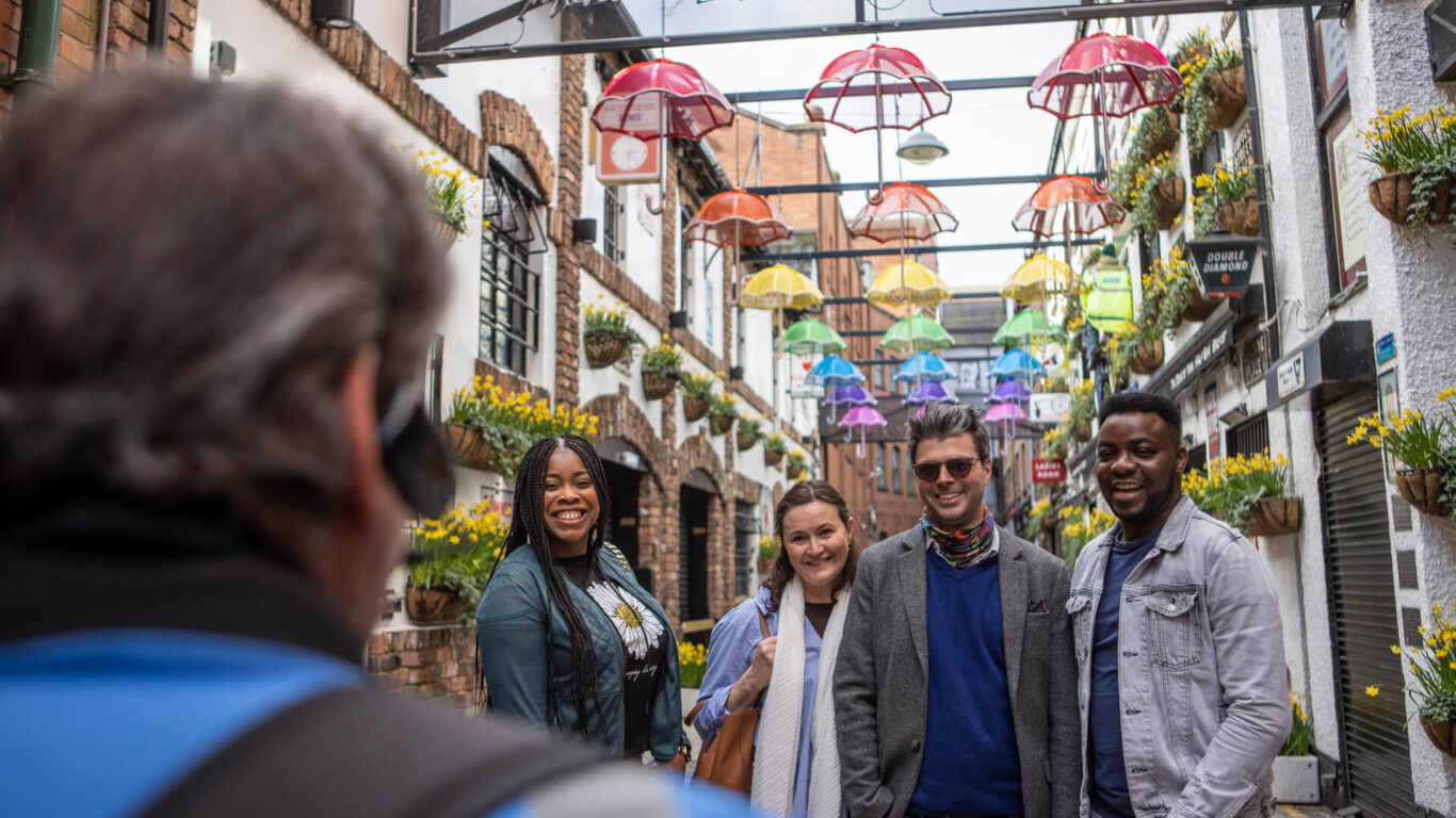 Guests enjoy a vibrant alley with colourful umbrellas and flower pots, capturing the lively and welcoming atmosphere.