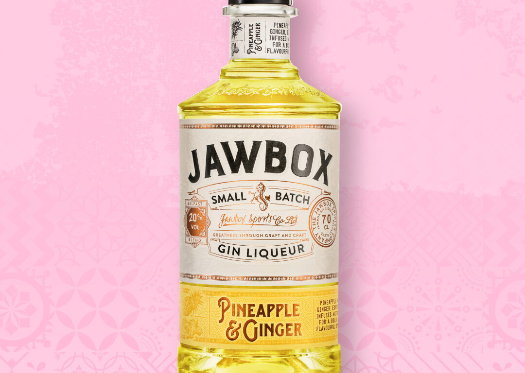 A bottle of yellow Jawbox Gin o a pink background
