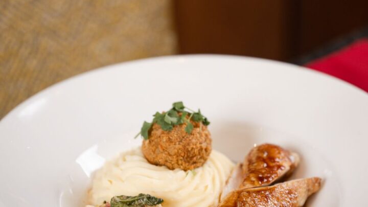 Delight in gourmet cuisine with tender chicken, creamy mash, and greens, showcasing the hotel's fine dining experience.