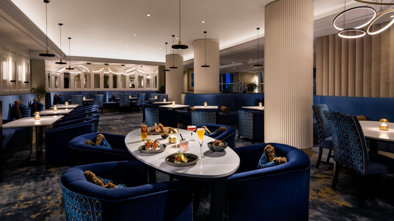 Elegant hotel dining area with blue plush seating, ambient lighting, and gourmet dishes, perfect for a cosy evening experience.